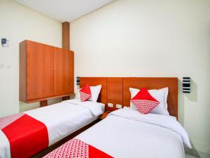- une chambre avec 2 lits dotés d'oreillers rouges et blancs dans l'établissement OYO 90341 Sean's Residence, à Medan