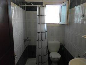 een badkamer met een toilet, een raam en een wastafel bij Tom's House in Skriperón