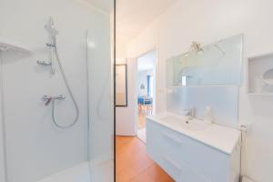 a white bathroom with a sink and a shower at Résidence Clemenceau 1 in Royan