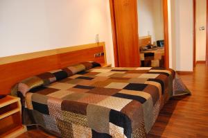 a bedroom with a bed with a checkered blanket on it at Hotel Galaico in Sanxenxo