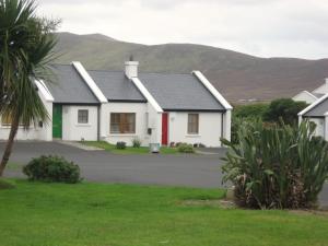 a white house with a red door and mountains in the background at Achill Sound HV No 7 in Achill Sound