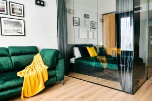 ein Wohnzimmer mit einem grünen Sofa und einem Spiegel in der Unterkunft EASY RENT Apartments - Diamond in Lublin
