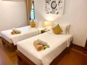 two beds in a hotel room with flowers on them at Smile House - Fisherman Village in Bophut