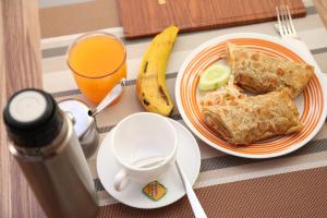 una mesa con un plato de comida y un vaso de zumo de naranja en Harts Motel en Kampala
