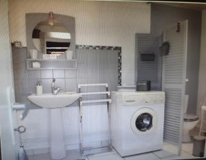 a bathroom with a washing machine and a sink at Maison Le Chatelet in Erquy