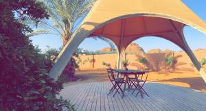 a table and chairs under a tent in the desert at Unique Farm Cottage in Al-ʿUla