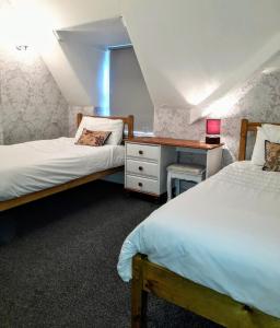 a bedroom with two beds and a dresser with a desk at Branstone Guest House in Llandudno