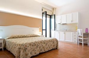 a bedroom with a bed and a table and a kitchen at Giardino Degli Ulivi Resort Masseria in Margherita di Savoia