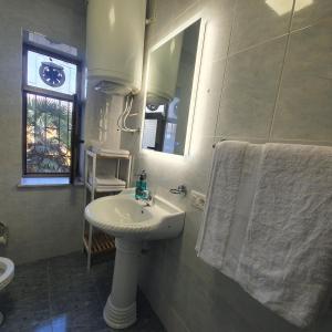 Baño blanco con lavabo y espejo en Central Home Away From Home, en Shkodër