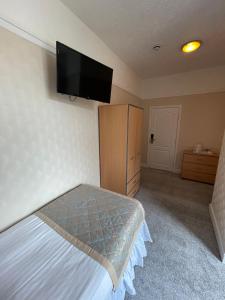 a bedroom with a bed and a tv on the wall at Queens Hotel, Skegness in Skegness