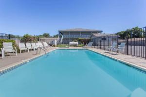 une grande piscine avec des chaises et une maison dans l'établissement Travelodge by Wyndham Clearlake, à Clearlake