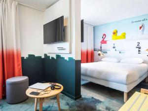 um quarto com uma cama, uma televisão e uma mesa em ibis Styles Thonon-les-Bains em Thonon-les-Bains