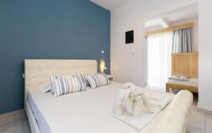 a bedroom with a large white bed with blue walls at Alexa's Sunny Days in Limenaria