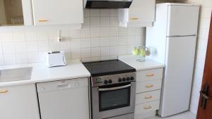 Il comprend une cuisine blanche équipée d'une cuisinière et d'un réfrigérateur. dans l'établissement Casa de Vilamoura, à Vilamoura