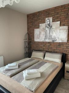 a bedroom with two beds and a brick wall at Apartamenty Bartnicza C in Bielsko-Biała