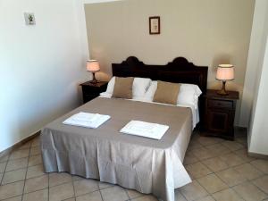 a bedroom with a bed with two tables and two lamps at Masseria Artemisia in Torre San Giovanni Ugento