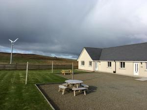 una mesa de picnic y un banco frente a un edificio en Eastbrae Cottages & Lodges, en Stromness