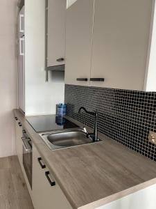 a kitchen with a sink and a black tile wall at Apartamenty Bartnicza C in Bielsko-Biała +27 photos