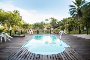 a pool on a wooden deck with white chairs and tables at Hotel Fazenda VCP in Silva Jardim