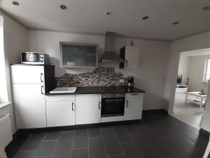 a kitchen with white cabinets and a stove top oven at Ferienwohnung John in Eisenach