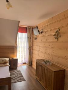 um quarto com paredes de madeira, uma cama e uma janela em Domki Magdalena przy termach chochołowskich em Witów