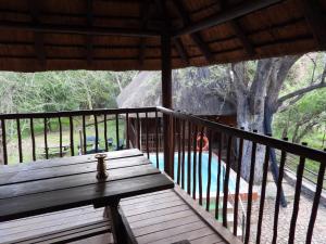 a wooden deck with a bench on a porch at Carpe Diem in Marloth Park