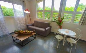 un soggiorno con un divano, un tavolo e delle sedie di Les gîtes de Bunel a Les Abymes