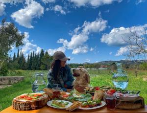 a woman and a dog sitting at a table with food at The Ranch in Kfar Hazîr