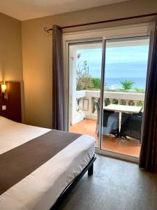 a bedroom with a bed and a view of the ocean at Hôtel Beau Soleil in Le Lavandou