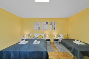 two beds in a room with yellow walls at DuMalux Garden in Subotica