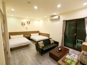 um quarto de hotel com duas camas e um sofá em 澎湖夏日南風民宿 em Magong
