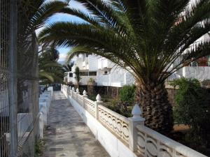 una recinzione bianca con palme su una strada di EL CHAPARRAL Studio-appartement with fantastic pool view and STRONG WIFI a Costa Del Silencio