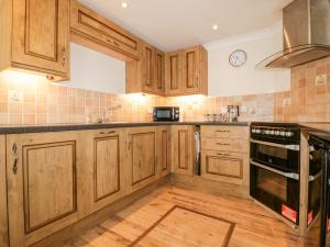 a kitchen with wooden cabinets and a stove top oven at Lower Brambleside in Truro