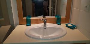 Un lavabo blanco en un baño con espejo. en Le Skisun - Massif et Parc national des Ecrins - Puy Saint Vincent 1800, en Puy-Saint-Vincent 25 fotos más