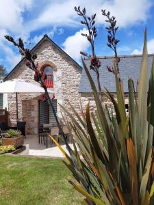 una casa de piedra con una mesa y una sombrilla en un patio en Maison Le Grès Rose, en Erquy