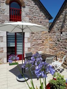 un patio con sombrilla y algunas flores púrpuras en Maison Le Grès Rose, en Erquy