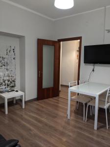 um quarto com uma mesa e cadeiras brancas e uma televisão em Verbania Centro Storico 2 camere em Verbania