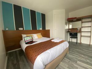 ein Schlafzimmer mit einem Bett und einem Laptop darauf in der Unterkunft Fasthotel Tours Nord in Parçay-Meslay