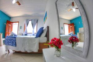 Zimmer mit einem Bett, einem Spiegel und Blumen in der Unterkunft Suites Casa Azul-Vila do Abraão- conforto, limpeza, ótima localização in Abraão