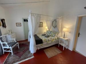 a bedroom with a canopy bed and a chair at Casa Olivia - Charming renovated farmhouse with panoramic views in Tavira