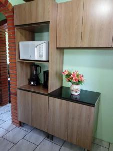 a kitchen with a counter with a microwave and flowers at Hospedaria das Azaleias in Novo Hamburgo