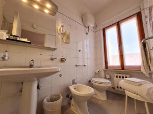 La salle de bains blanche est pourvue d'un lavabo et de toilettes. dans l'établissement Hotel Da Graziano, à San Gimignano