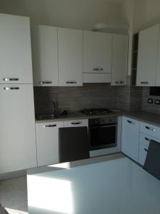 uma cozinha com armários brancos e um forno com placa de fogão em ORIZZONTE SUL MARE em Savona
