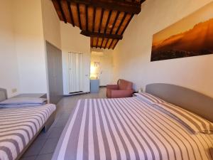 een slaapkamer met 2 bedden en een stoel bij Hotel Da Graziano in San Gimignano