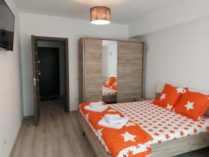 sypialnia z łóżkiem z pomarańczową i białą pościelą w obiekcie BYA Luxury w mieście Valea Lupului
