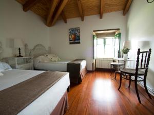 a bedroom with two beds and a table and a window at Casa Blanco in Palas de Rei 