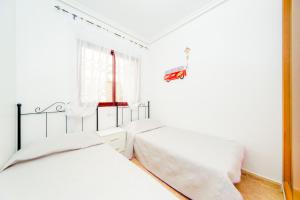 a white bedroom with two beds and a window at Apartamento COSTAMARINA in Cabo Roig +14 photos