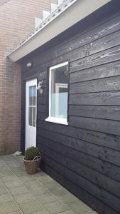un edificio negro con una ventana y una cesta en 't Koerhaus, en Egmond aan Zee