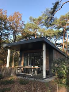 a small house with a black roof and a table in front of trees at Natuurhuisje Pine & Oak 6 persoons in Hardenberg