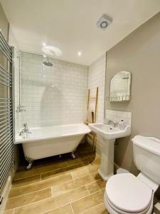a bathroom with a tub and a toilet and a sink at Nickleby Nook By the Sea - Meters to the Beach! in Broadstairs